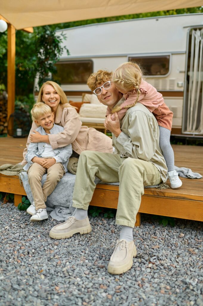 Happy family poses at the trailer, summer camping